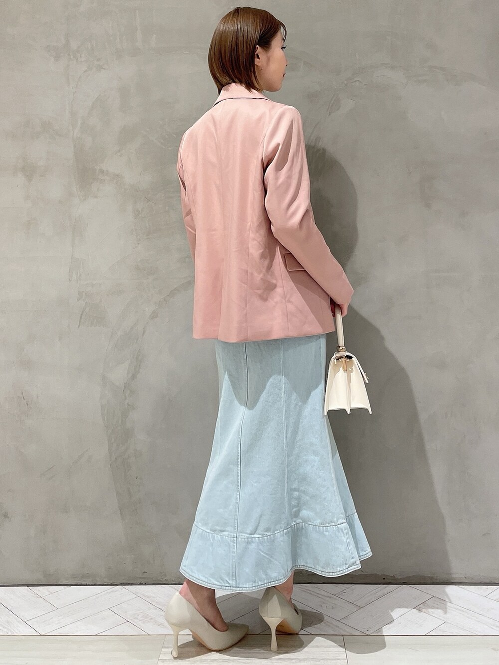 ホワイト系のハンドバッグ、ホワイト系のパンプス、ブルー系のデニムスカートを着用したレディースの冬コーディネートの6枚目の写真