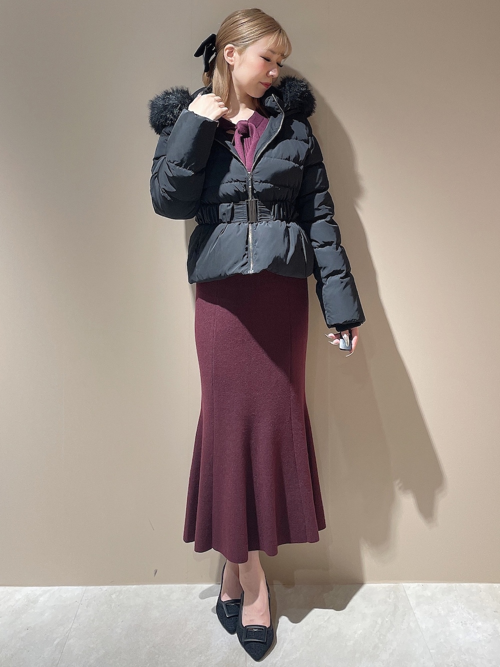 レッド系のワンピース、ブラック系のパンプス、ブラック系のダウンジャケット/コートを着用したレディースの秋コーディネートの5枚目の写真