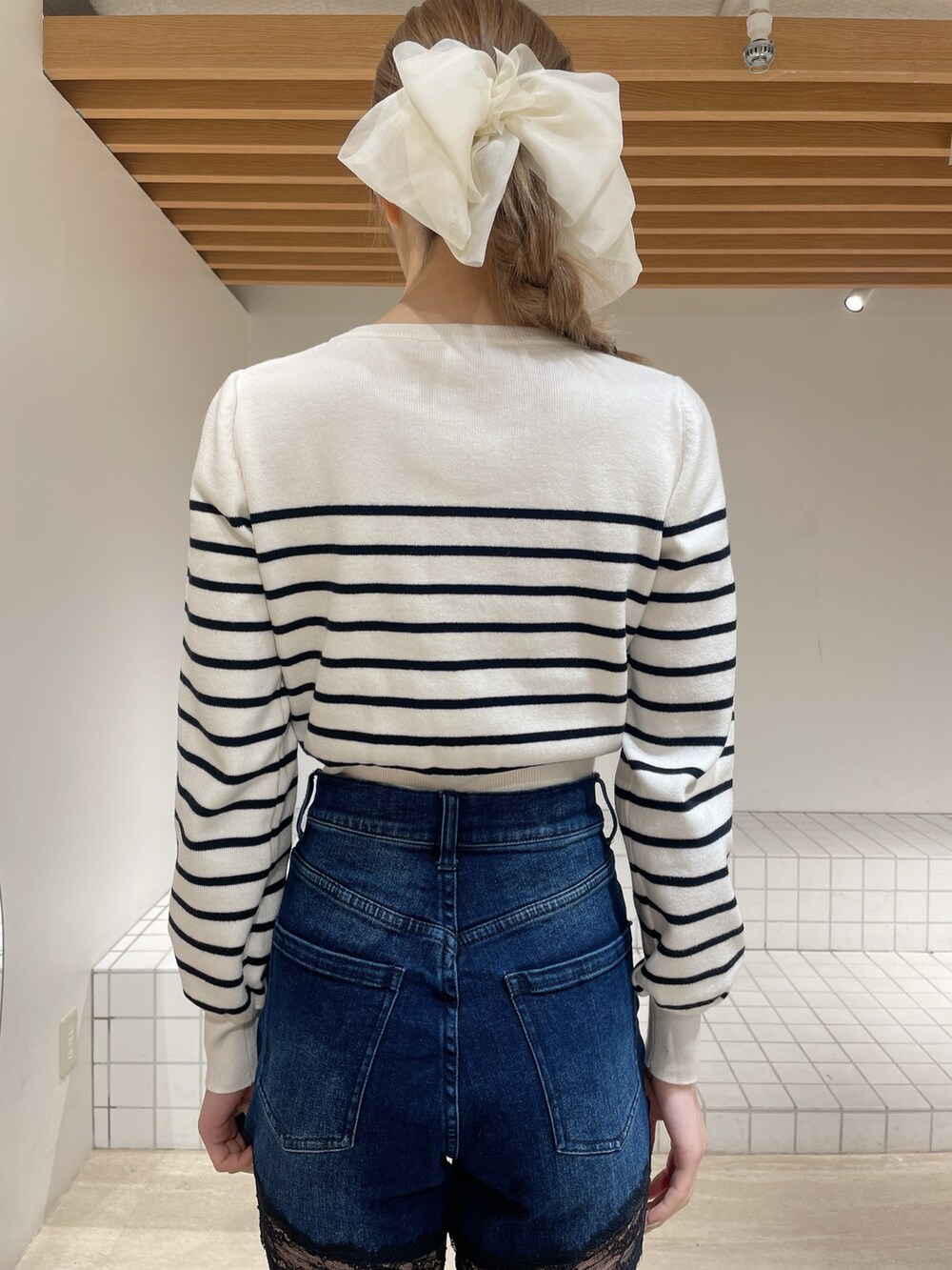 ホワイト系のカーディガン/ボレロ、ブルー系のデニムパンツ、ホワイト系のブーツを着用したレディースの春コーディネートの5枚目の写真