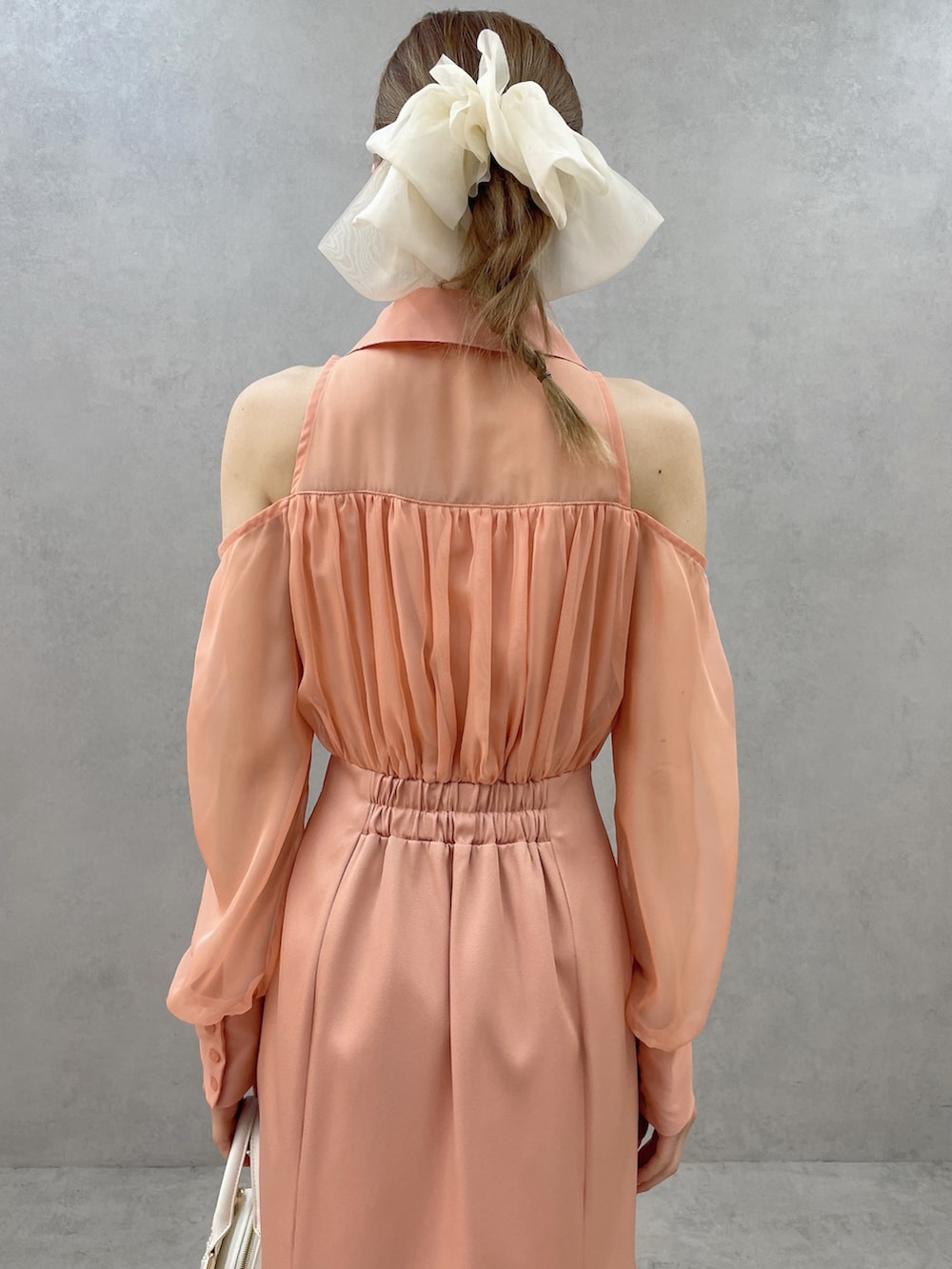 オレンジ系のワンピース、ホワイト系のハンドバッグ、ホワイト系のサンダルを着用したレディースの春コーディネートの6枚目の写真