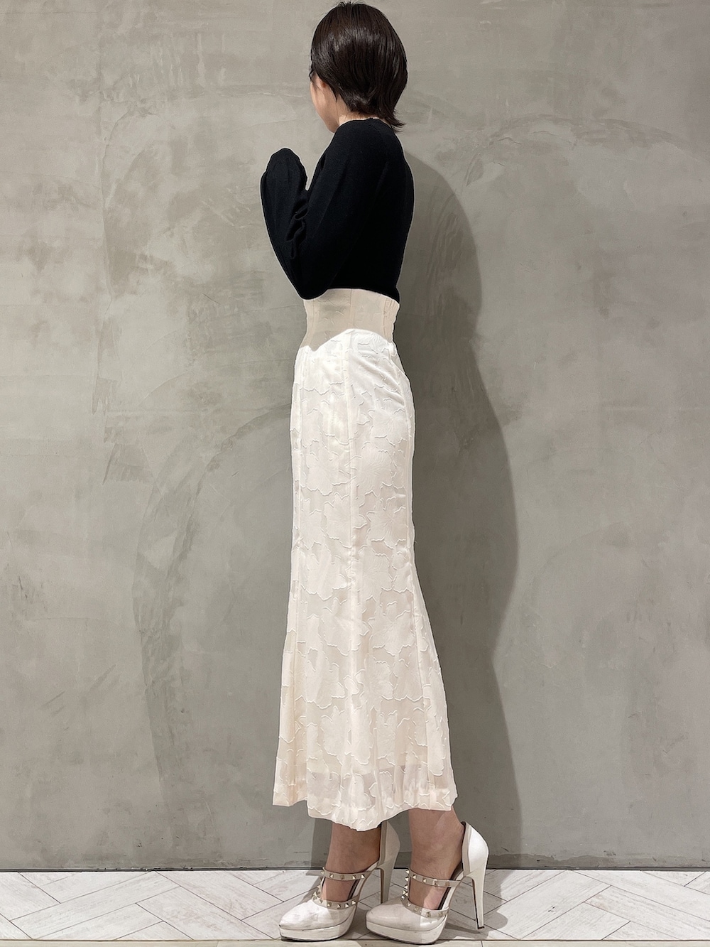 ホワイト系のパンプス、ホワイト系のスカート、ブラック系のニット/セーターを着用したレディースの冬コーディネートの2枚目の写真