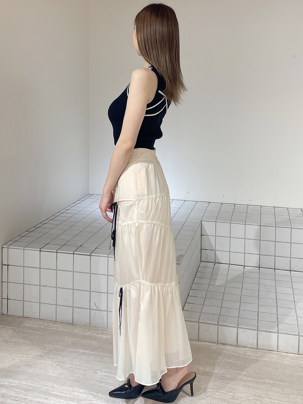 ブラック系のパンプス、ホワイト系のスカート、ブラック系のタンクトップを着用したレディースの夏コーディネートの3枚目の写真