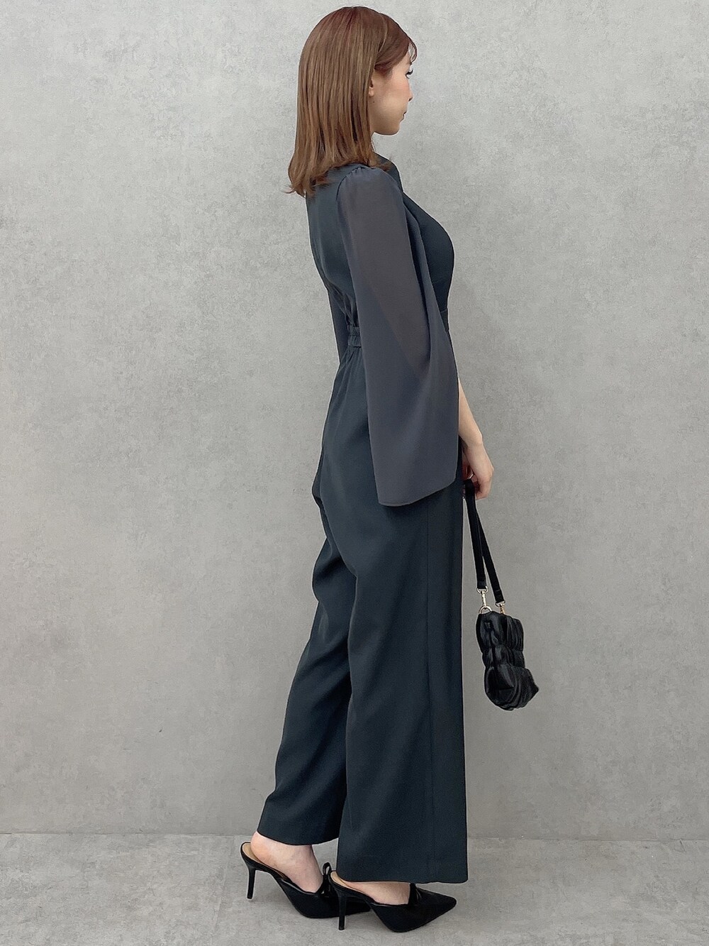 グレー系のつなぎ/オールインワン、ブラック系のハンドバッグ、ブラック系のパンプスを着用したレディースの冬コーディネートの4枚目の写真