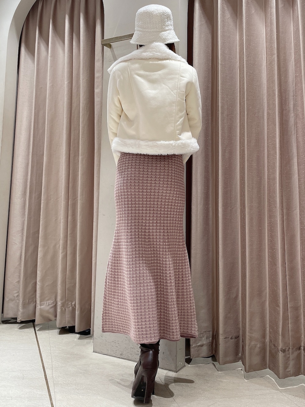 ピンク系のワンピース、ブラウン系のブーツ、ホワイト系のハットを着用したレディースの冬コーディネートの6枚目の写真