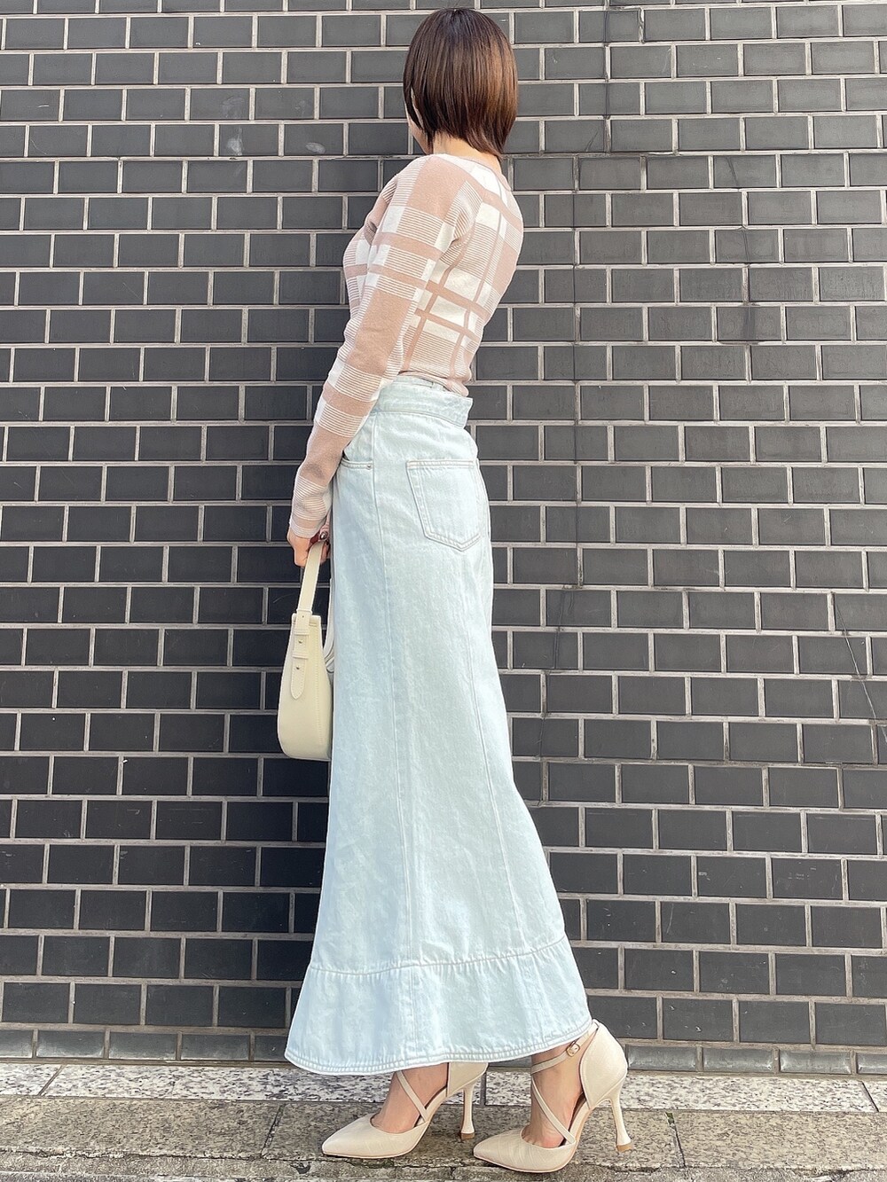 その他のニット/セーター、ホワイト系のハンドバッグ、ブルー系のデニムスカートを着用したレディースの冬コーディネートの4枚目の写真