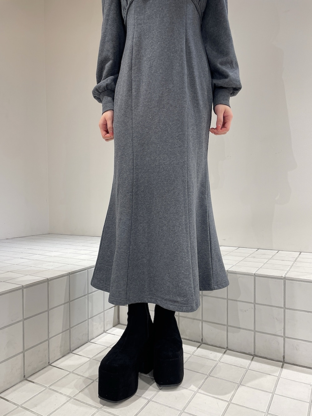 グレー系のワンピース、ブラック系のブーツ、グレー系のシュシュを着用したレディースの秋コーディネートの6枚目の写真