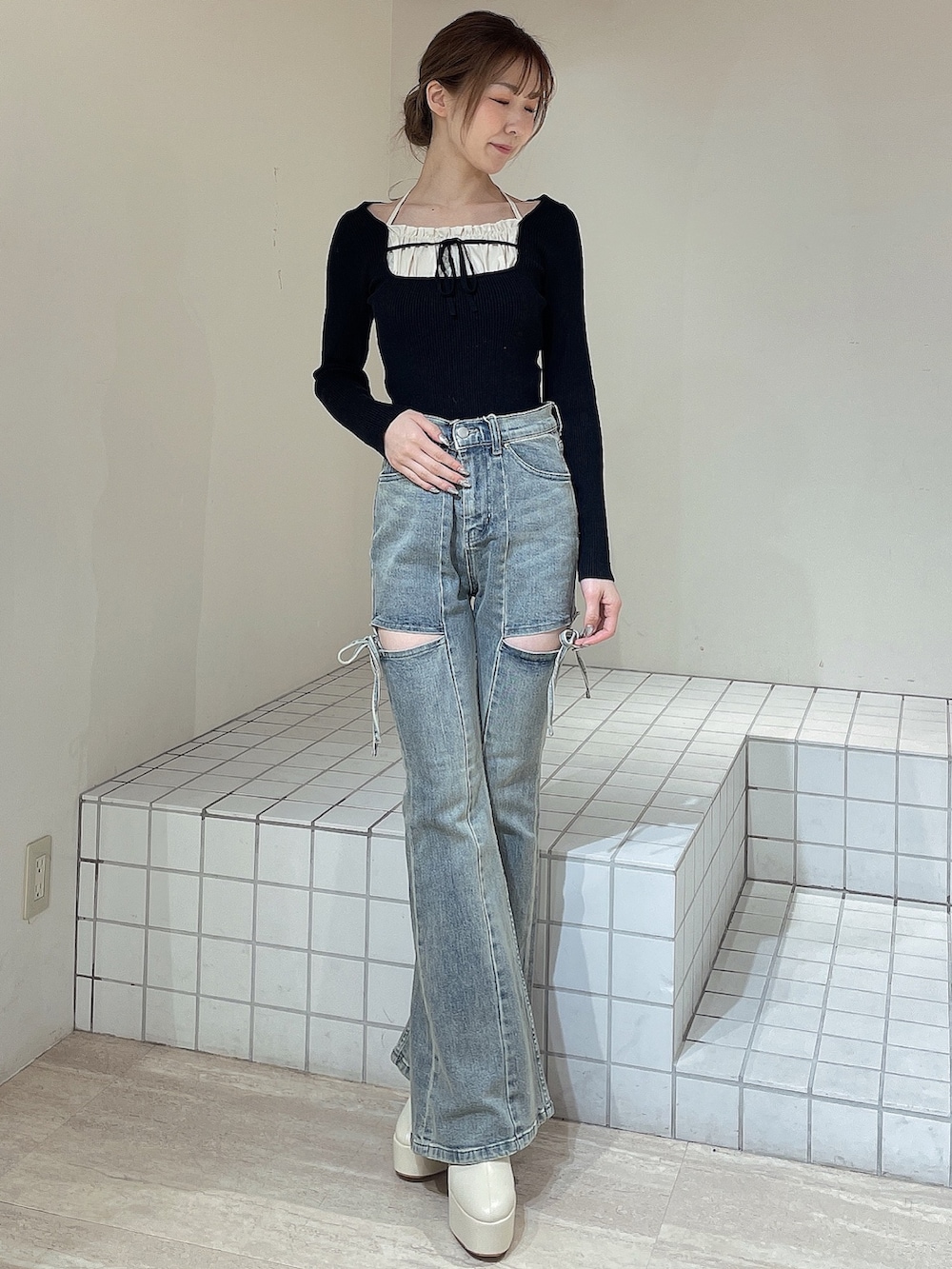 ブラック系のニット/セーター、ブルー系のデニムパンツ、ホワイト系のブーツを着用したレディースの冬コーディネートの2枚目の写真