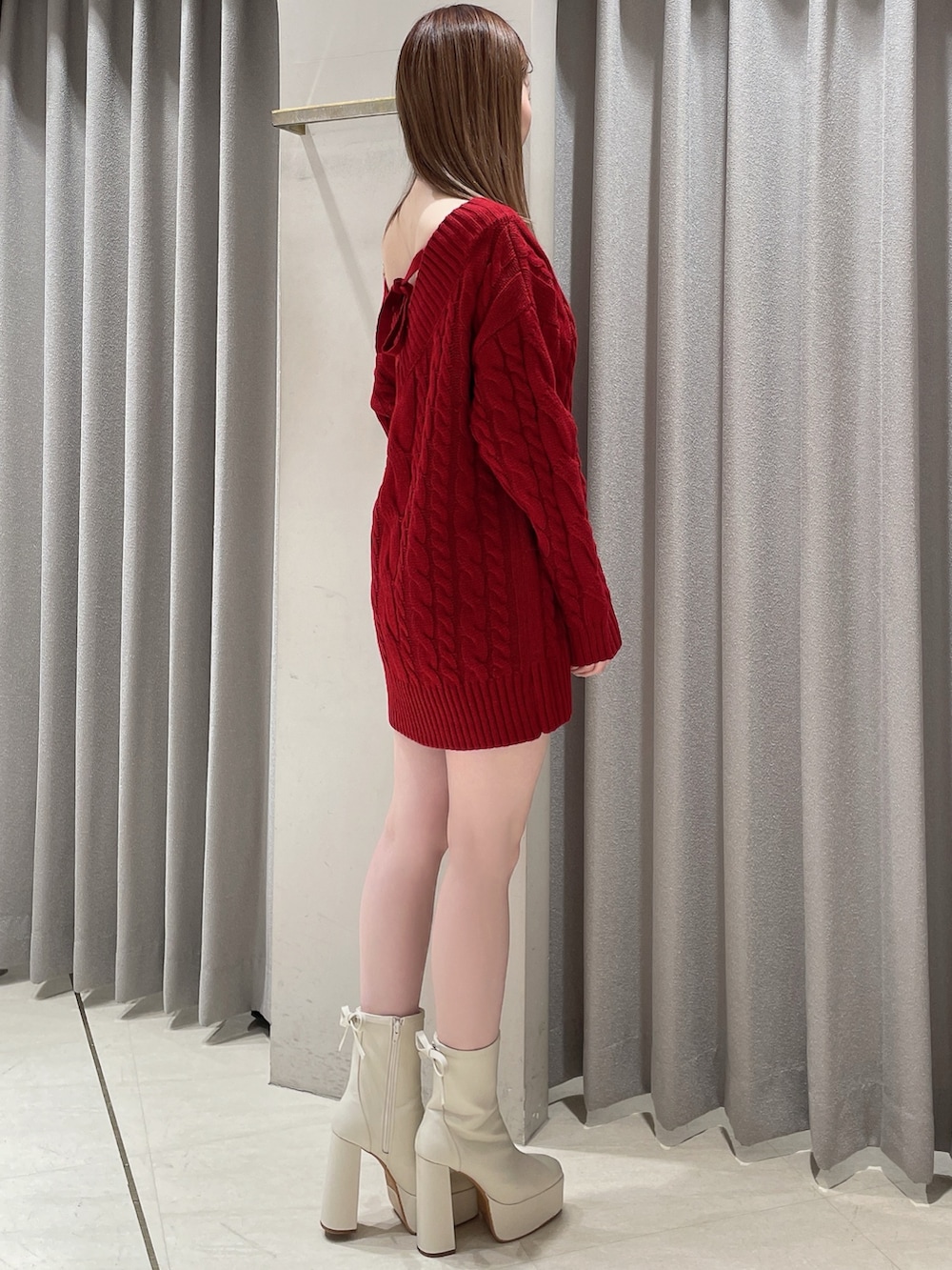 レッド系のニット/セーター、ホワイト系のスカート、ホワイト系のショルダーバッグを着用したレディースの冬コーディネートの3枚目の写真