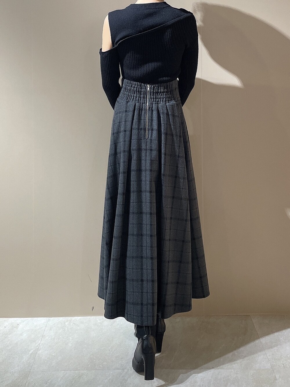 ブラック系のニット/セーター、ブラック系のスカート、ブラック系のブーツを着用したレディースの秋コーディネートの5枚目の写真