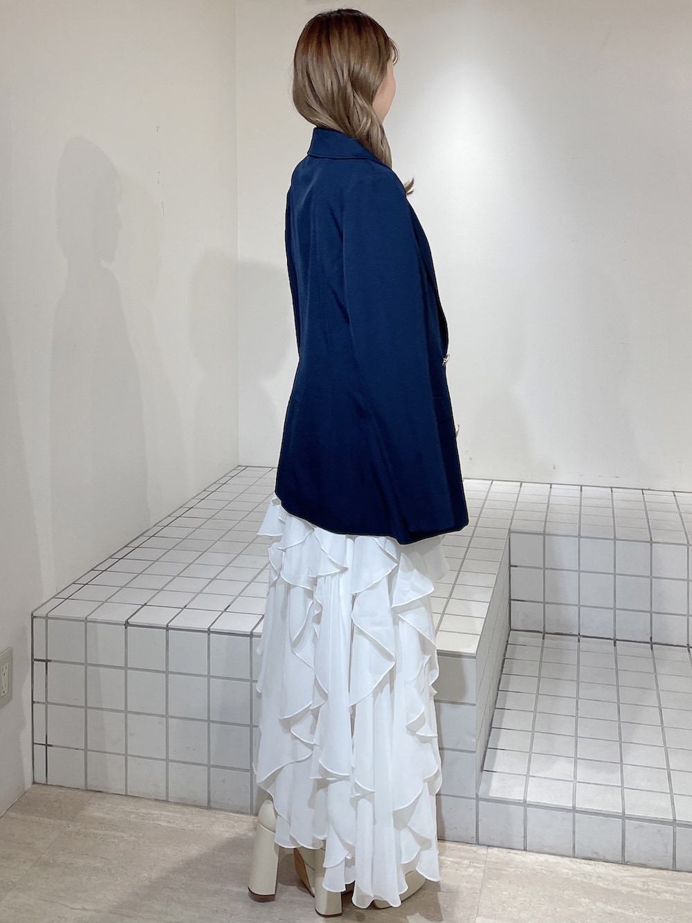 ブルー系のテーラードジャケット、レッド系のニット/セーター、ホワイト系のスカートを着用したレディースの冬コーディネートの3枚目の写真