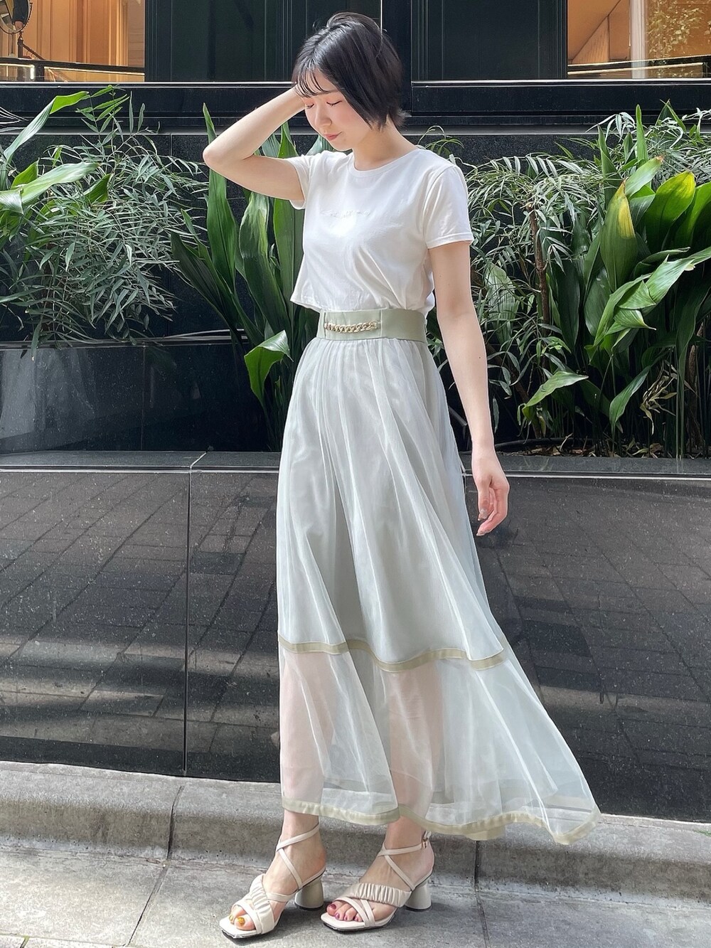 グリーン系のスカート、ホワイト系のサンダル、ホワイト系のTシャツ/カットソーを着用したレディースの春コーディネートの2枚目の写真