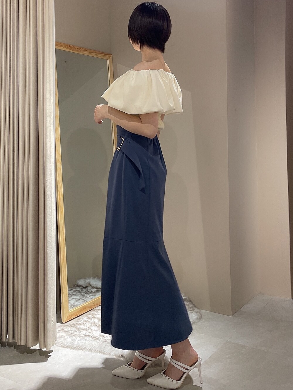 ホワイト系のニット/セーター、ブルー系のスカート、ホワイト系のパンプスを着用したレディースの春コーディネートの2枚目の写真