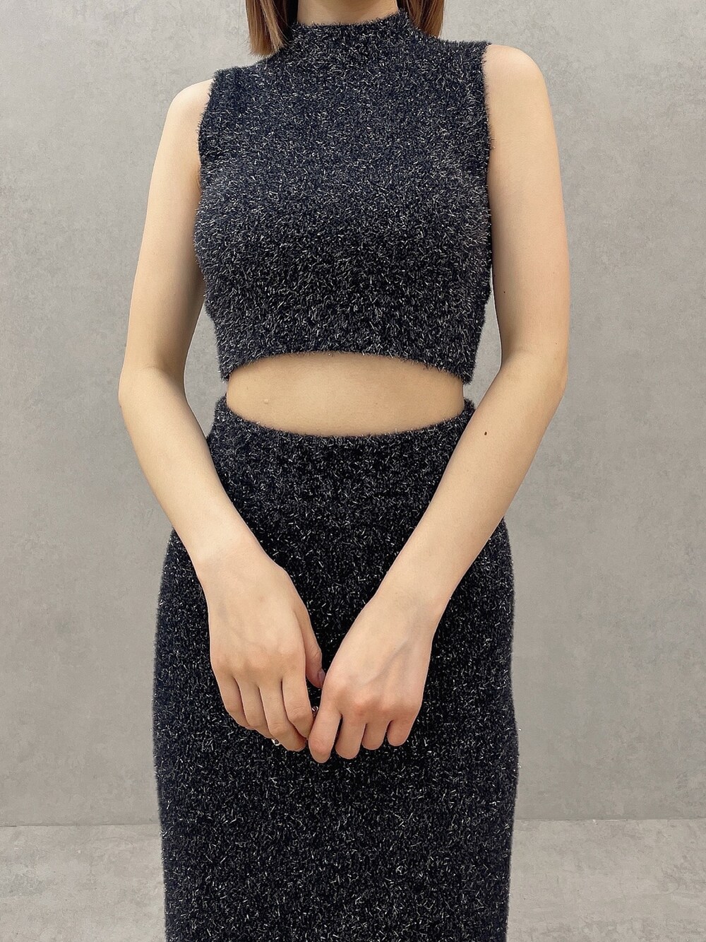 ブラック系のニット/セーター、ブラック系のスカート、ホワイト系のパンプスを着用したレディースの夏コーディネートの5枚目の写真