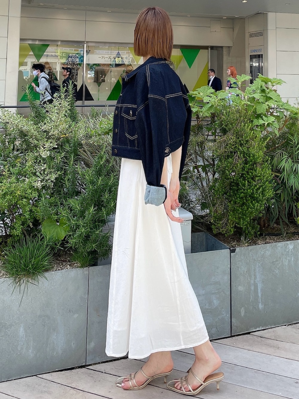 ホワイト系のワンピース、ブルー系のデニムジャケット、ゴールド系のサンダルを着用したレディースの春コーディネートの3枚目の写真