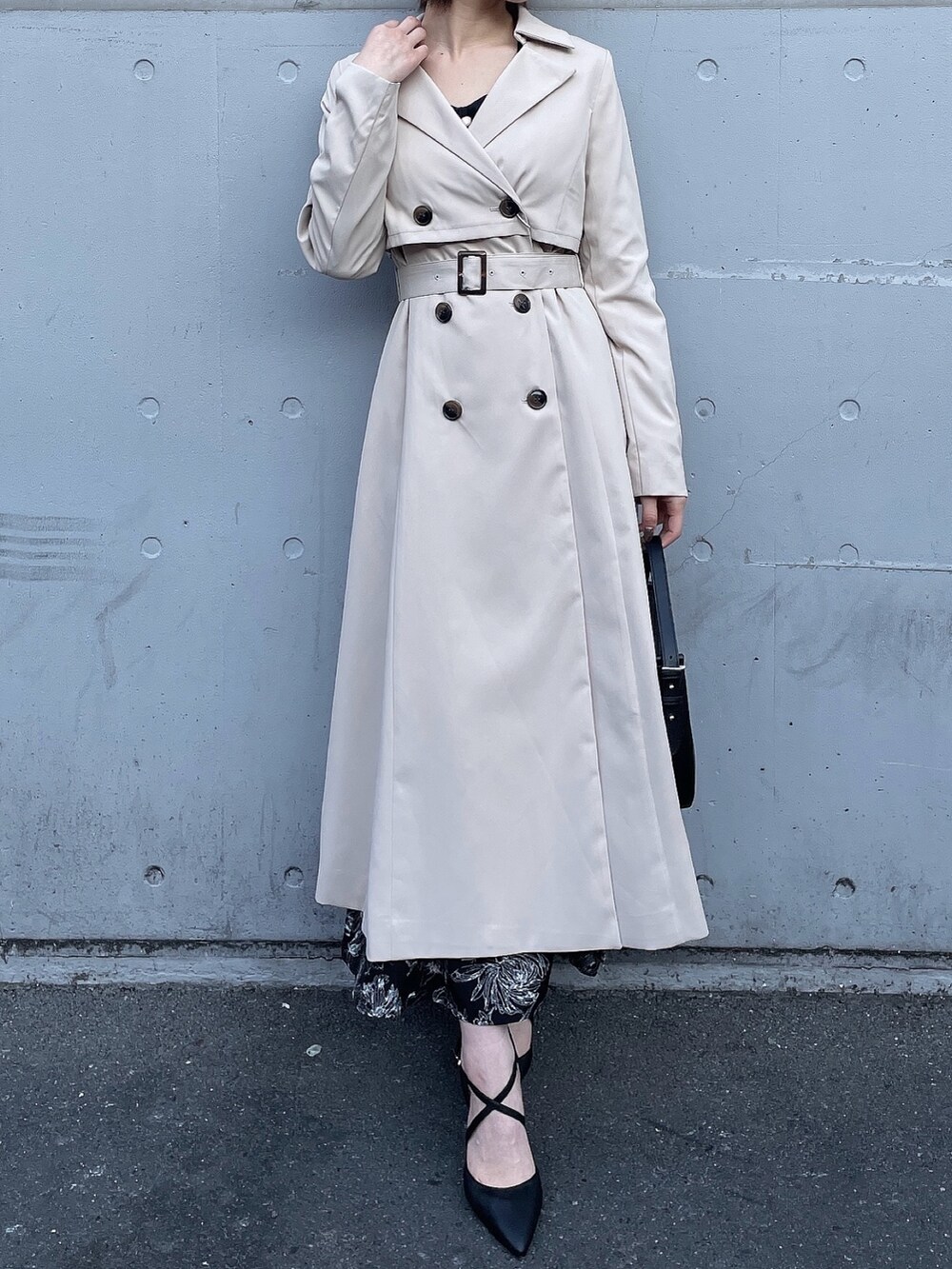 ベージュ系のトレンチコート、ブラック系のワンピース、ブラック系のハンドバッグを着用したレディースの冬コーディネートの5枚目の写真