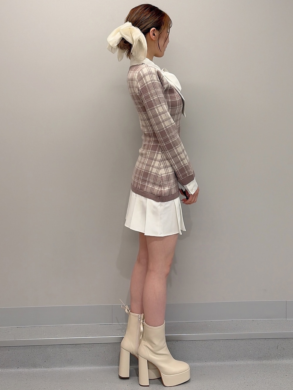 ベージュ系のワンピース、ホワイト系のブーツ、ホワイト系のバレッタ/ヘアクリップを着用したレディースの冬コーディネートの3枚目の写真
