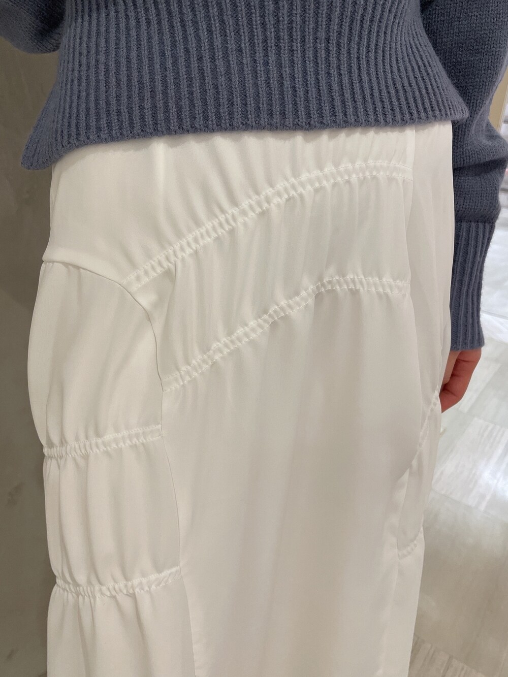 ホワイト系のブーツ、ホワイト系のハンドバッグ、ブルー系のニット/セーターを着用したレディースの冬コーディネートの6枚目の写真