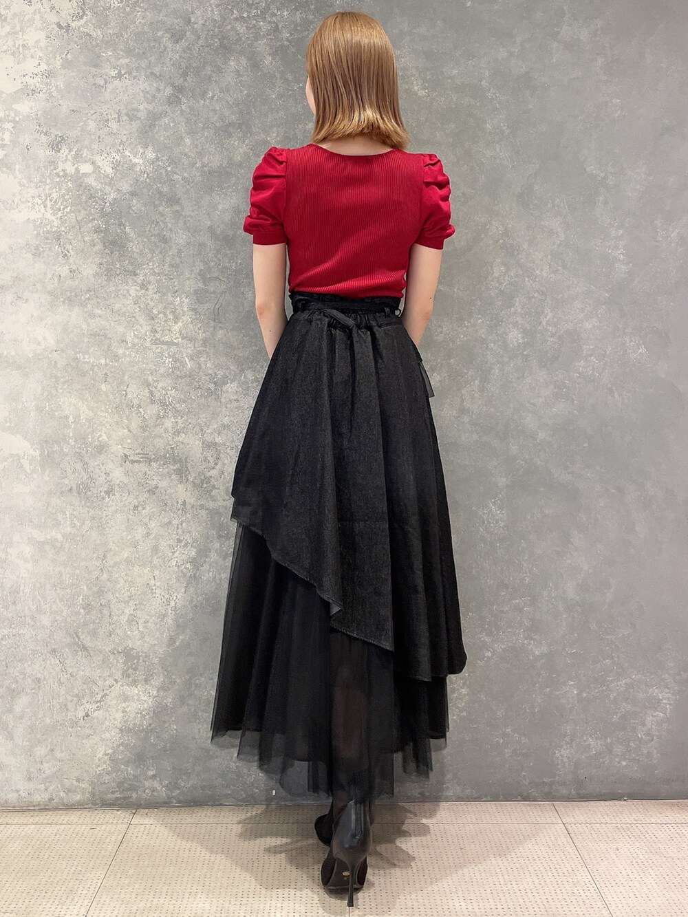 レッド系のニット/セーター、ブラック系のデニムスカート、ブラック系のブーツを着用したレディースの夏コーディネートの4枚目の写真