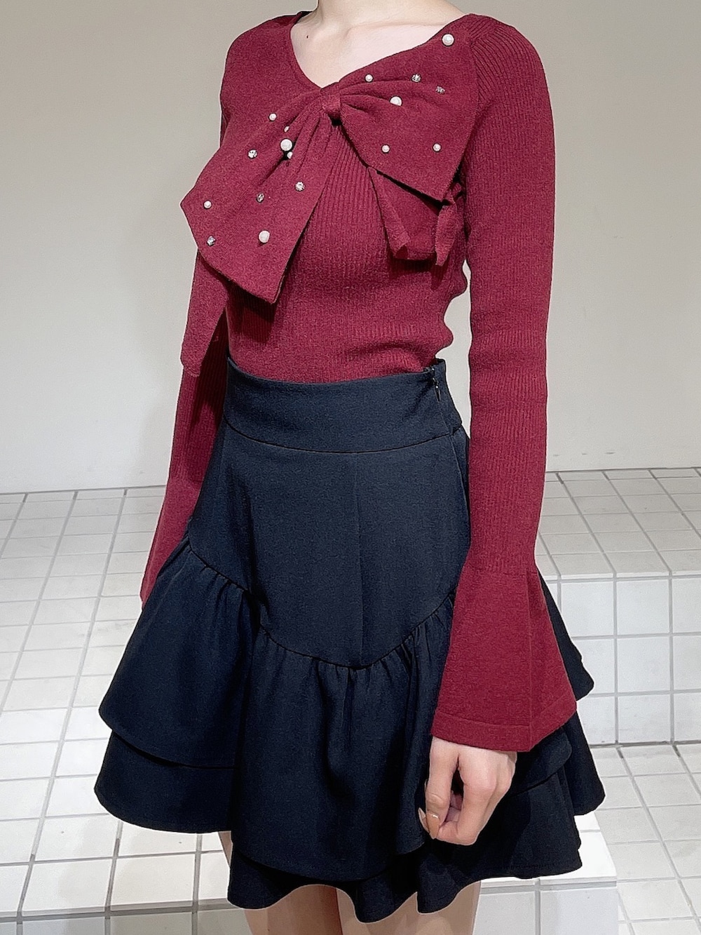 レッド系のニット/セーター、ブラック系のスカート、ブラック系のブーツを着用したレディースの冬コーディネートの6枚目の写真