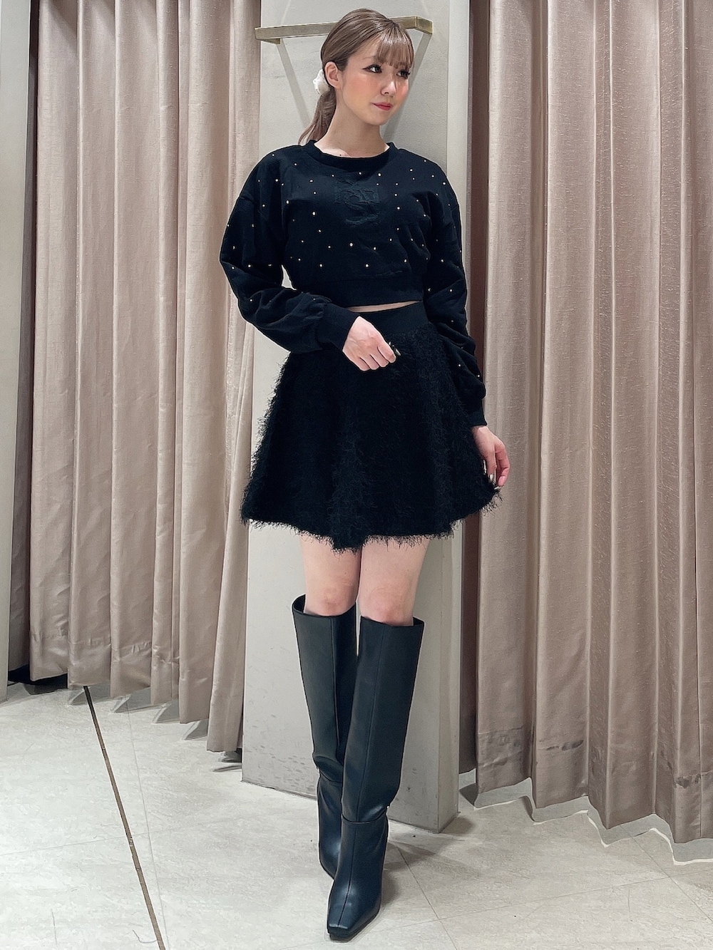 ブラック系のスウェット、ブラック系のスカート、ブラック系のブーツを着用したレディースの秋コーディネートの2枚目の写真