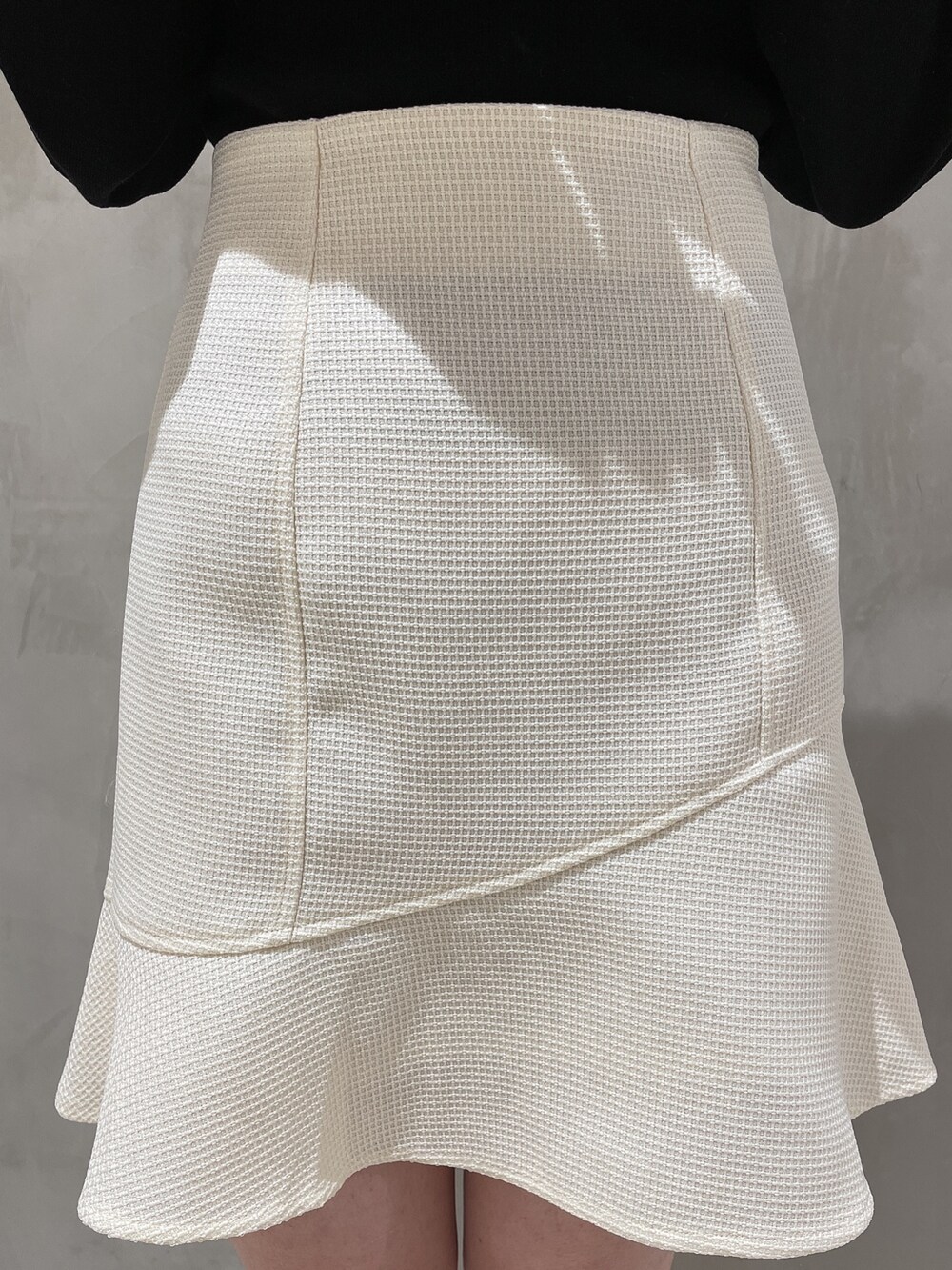 ホワイト系のテーラードジャケット、ホワイト系のスカート、ブラック系のニット/セーターを着用したレディースの冬コーディネートの7枚目の写真