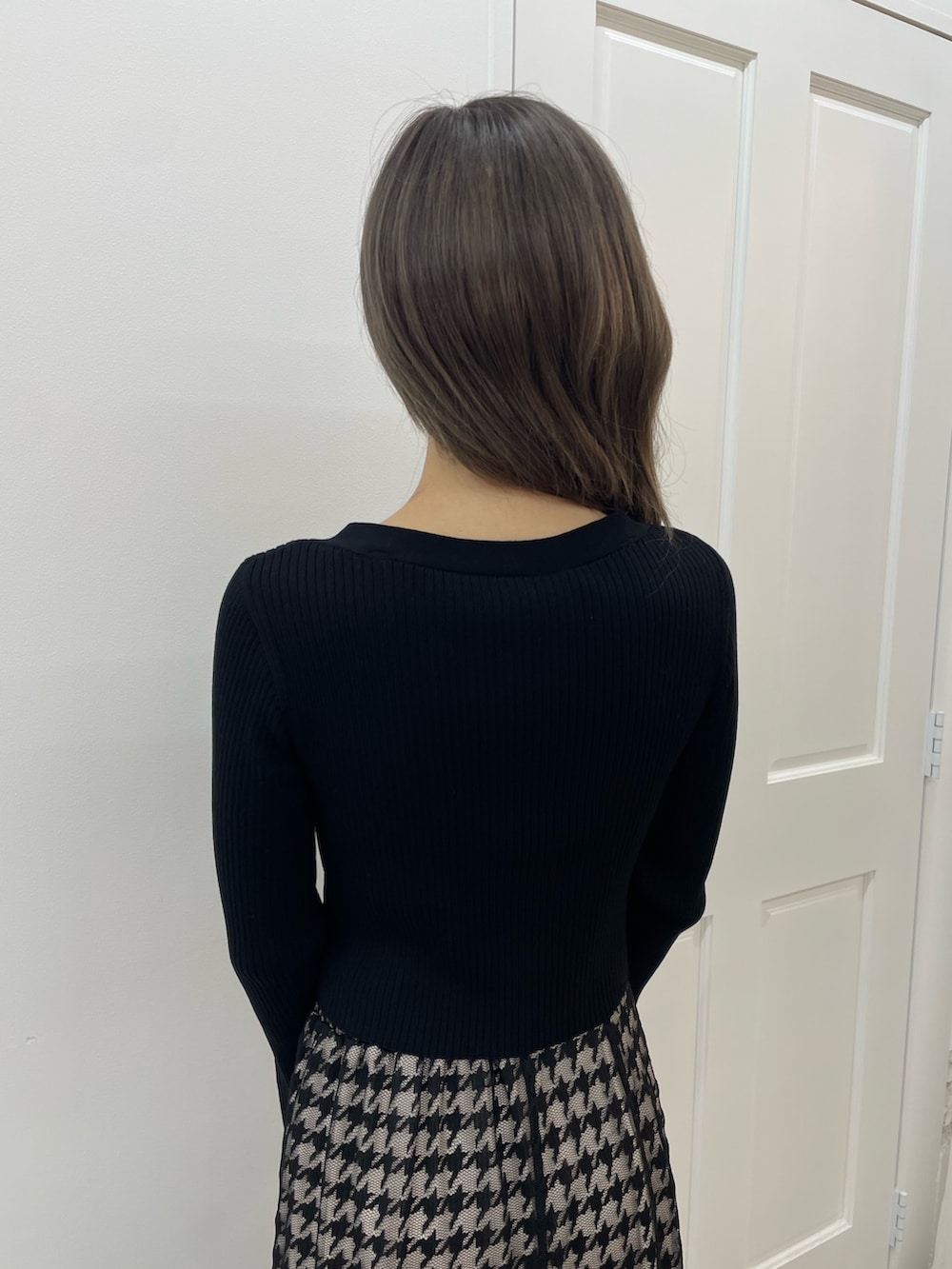 ブラック系のニット/セーター、ブラック系のスカート、ブラック系のブーツを着用したレディースの秋コーディネートの7枚目の写真