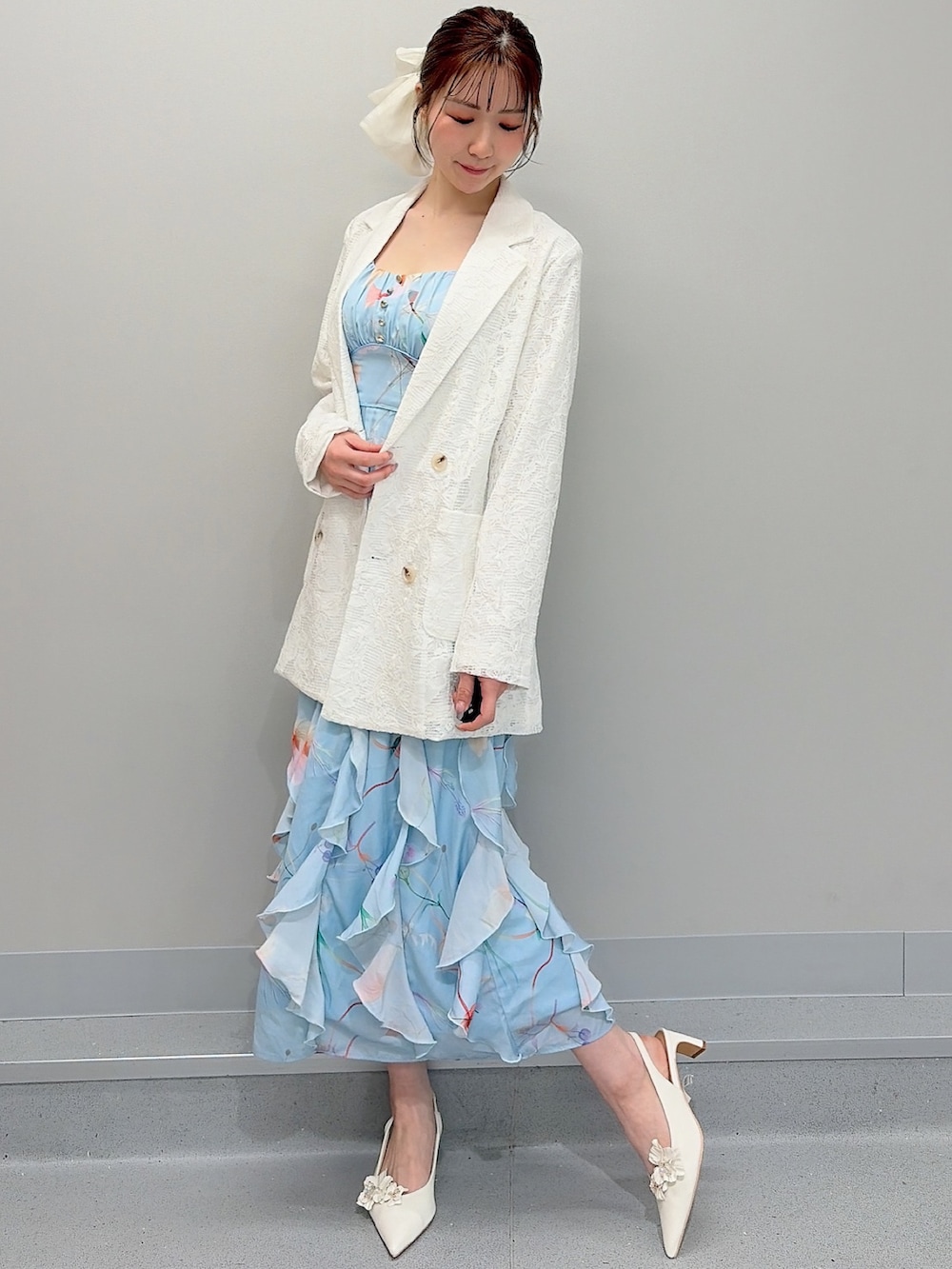 ホワイト系のテーラードジャケット、ブルー系のワンピース、ホワイト系のパンプスを着用したレディースの冬コーディネートの2枚目の写真