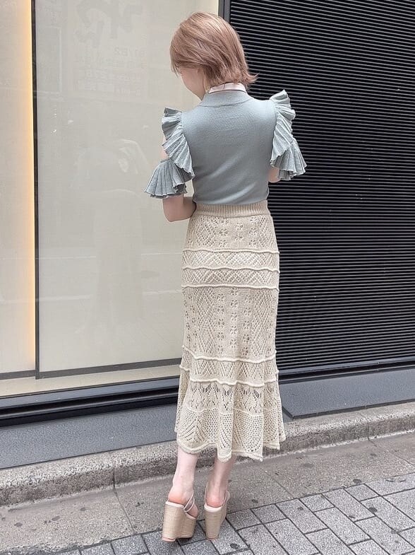 ベージュ系のスカート、ホワイト系のサンダル、グリーン系のニット/セーターを着用したレディースの春コーディネートの3枚目の写真