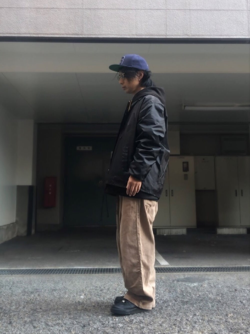 ブラック系のナイロンジャケット、ホワイト系のスニーカー、ベージュ系のベルトを着用したメンズの冬コーディネートの2枚目の写真
