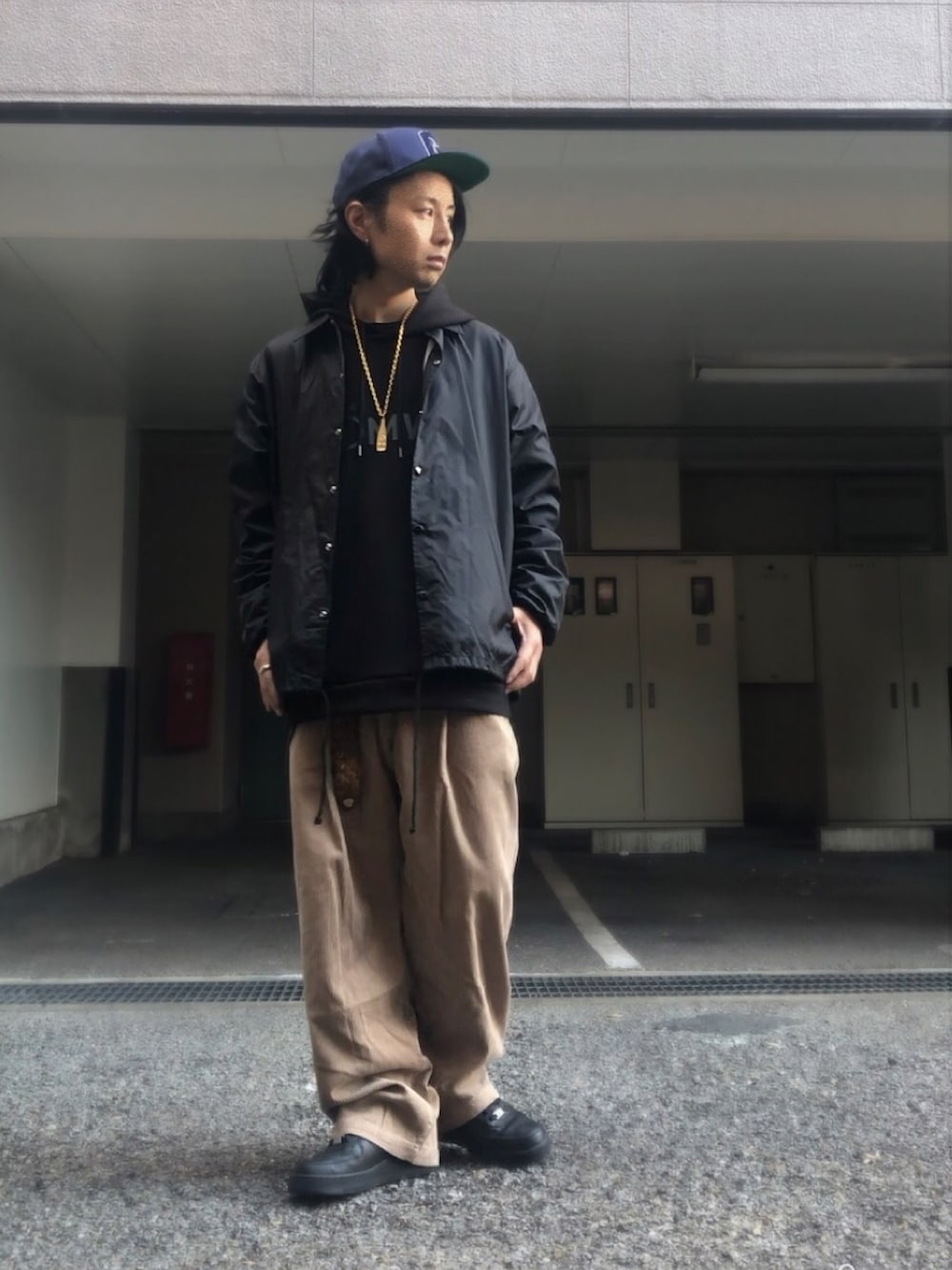 ブラック系のナイロンジャケット、ホワイト系のスニーカー、ベージュ系のベルトを着用したメンズの冬コーディネートの4枚目の写真