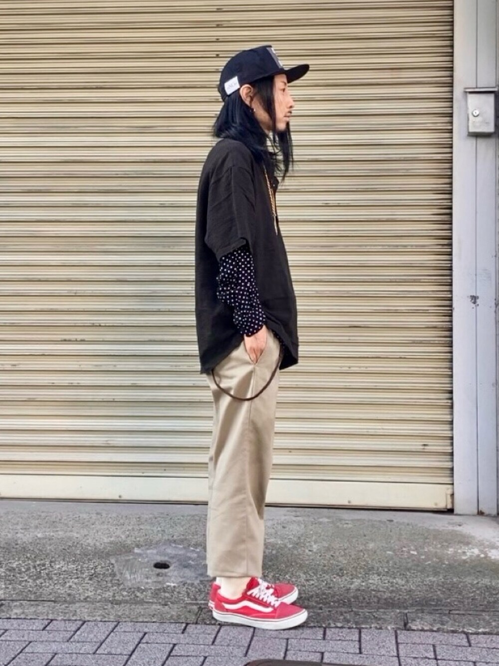 ベージュ系のチノパンツ、レッド系のスニーカー、ブラック系のTシャツ/カットソーを着用したメンズの春コーディネートの2枚目の写真