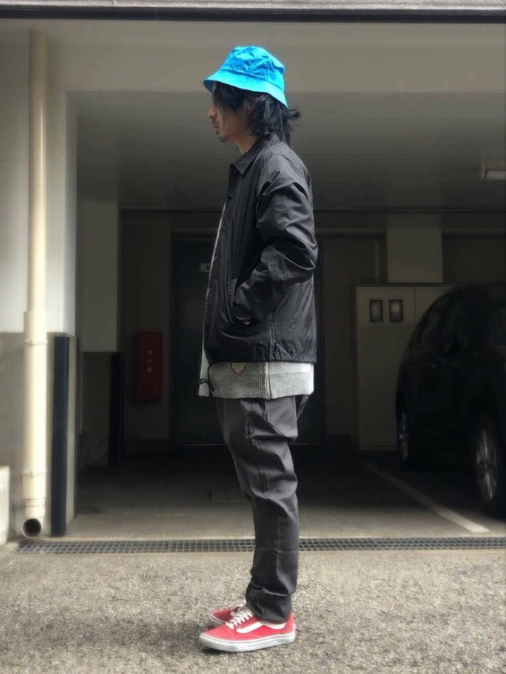 グレー系のニット/セーター、ブラック系のナイロンジャケット、レッド系のスニーカーを着用したメンズの冬コーディネートの2枚目の写真