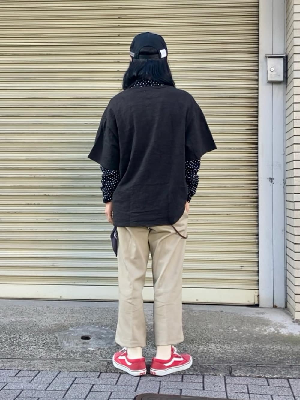 ベージュ系のチノパンツ、レッド系のスニーカー、ブラック系のTシャツ/カットソーを着用したメンズの春コーディネートの3枚目の写真
