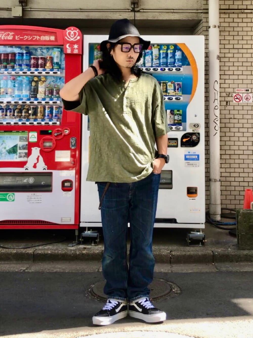 グリーン系のTシャツ/カットソー、ブラック系のスニーカー、ブルー系のデニムパンツを着用したメンズの秋コーディネートの2枚目の写真