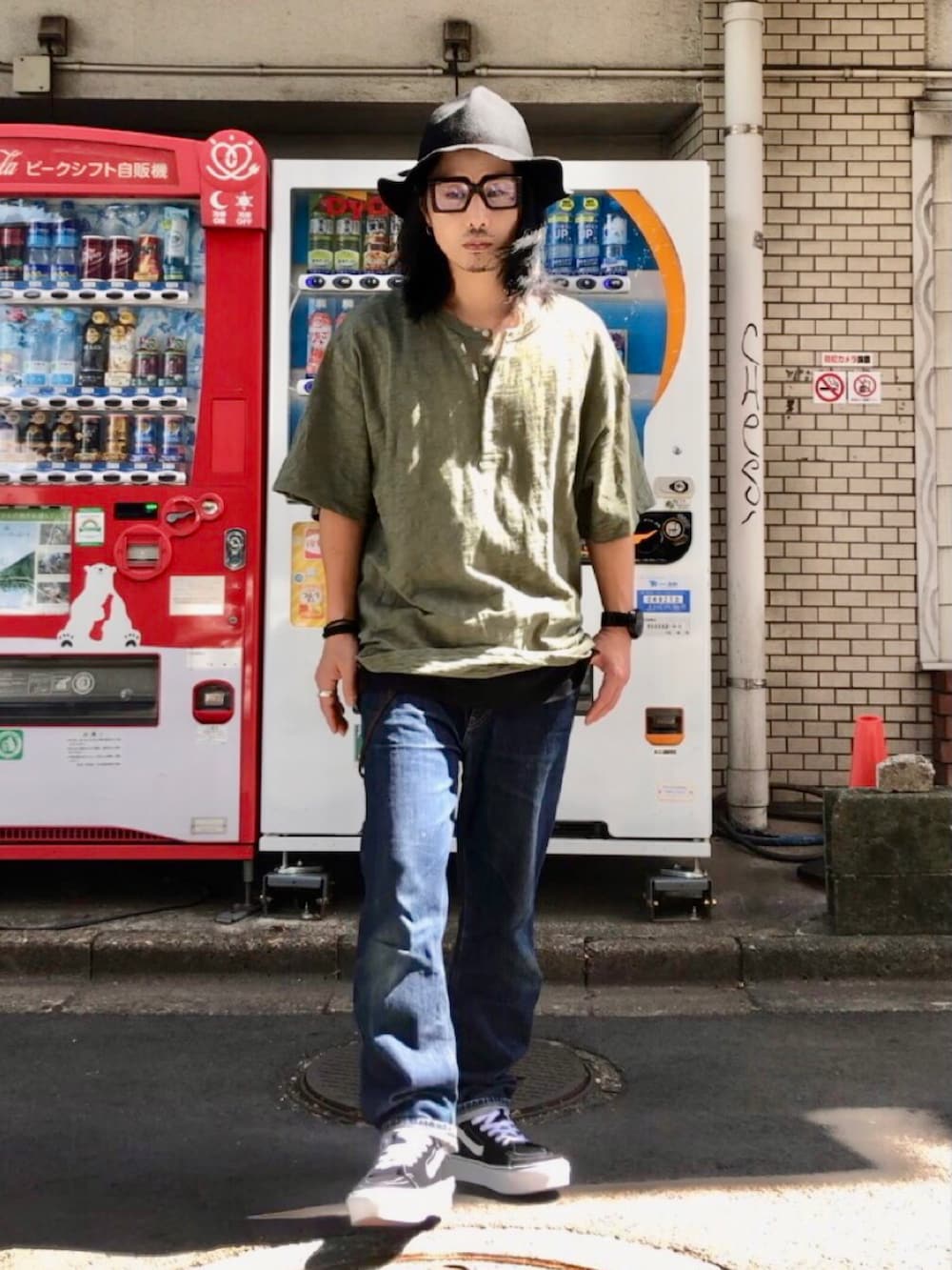 グリーン系のTシャツ/カットソー、ブラック系のスニーカー、ブルー系のデニムパンツを着用したメンズの秋コーディネートの5枚目の写真