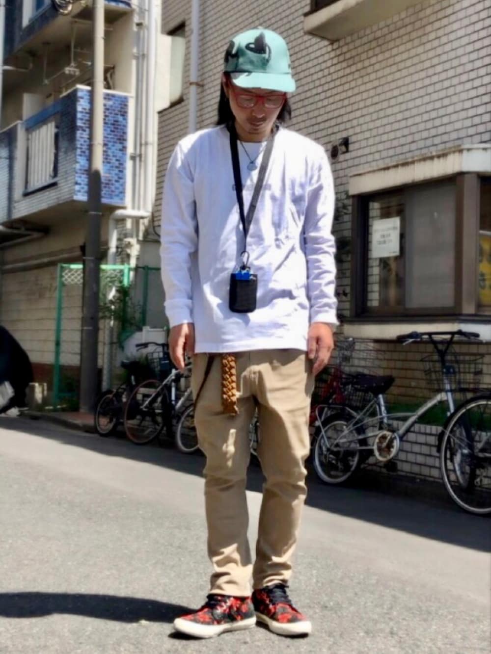 ホワイト系のTシャツ/カットソー、ベージュ系のチノパンツ、その他のスニーカーを着用したメンズの春コーディネートの4枚目の写真