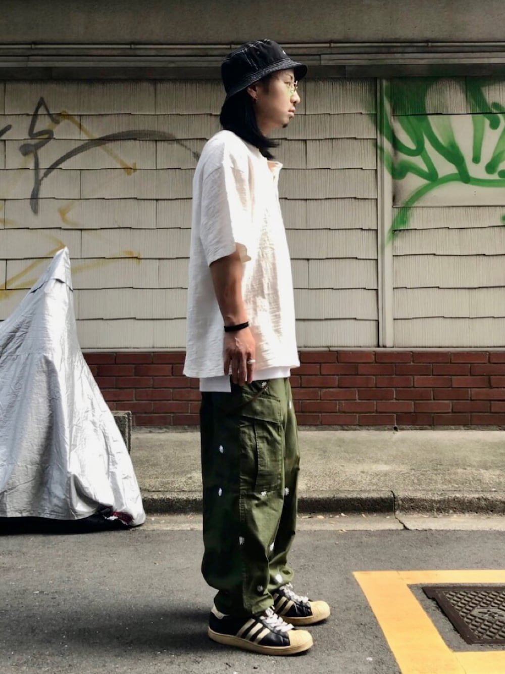 ホワイト系のTシャツ/カットソー、グリーン系のカーゴパンツ、ブラック系のスニーカーを着用したメンズの秋コーディネートの3枚目の写真