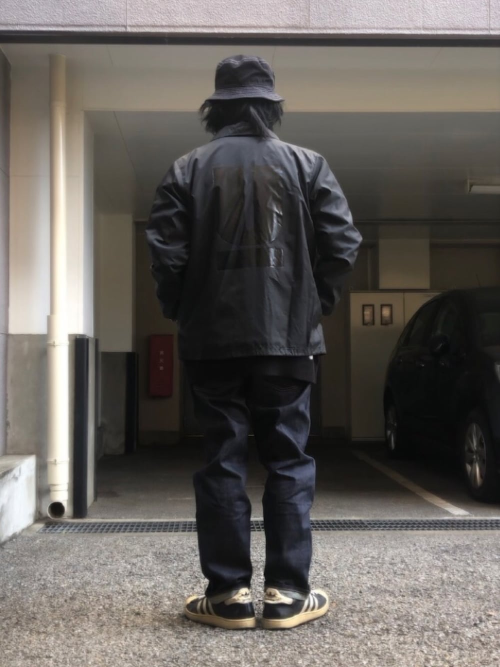 ブラック系のナイロンジャケット、ブラック系のニット/セーター、ブラック系のスニーカーを着用したメンズの冬コーディネートの3枚目の写真