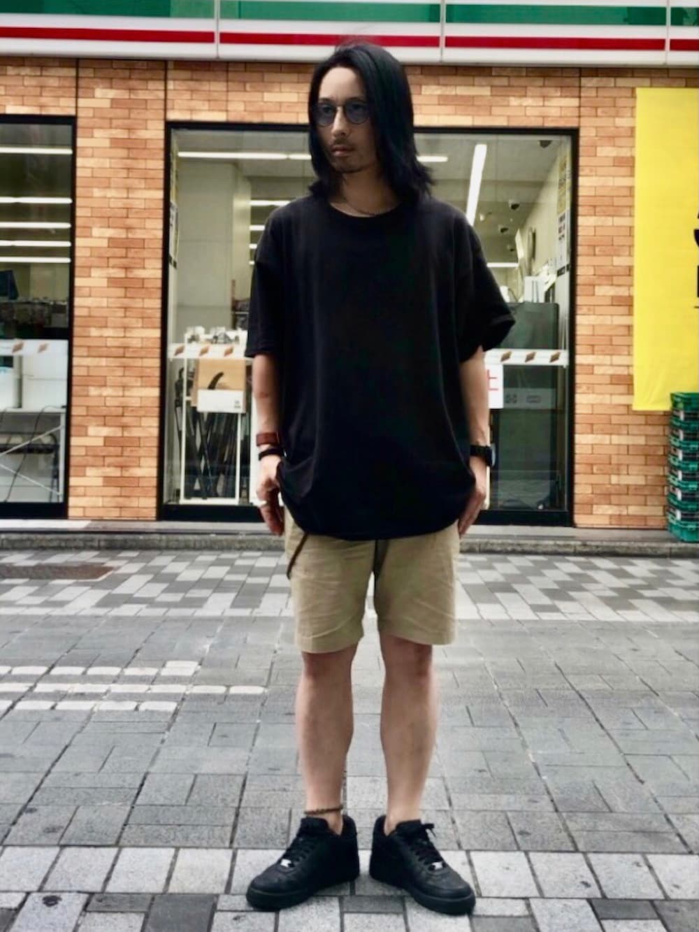 ホワイト系のスニーカー、ホワイト系のTシャツ/カットソー、ブラウン系のバングル/リストバンドを着用したメンズの夏コーディネートの3枚目の写真