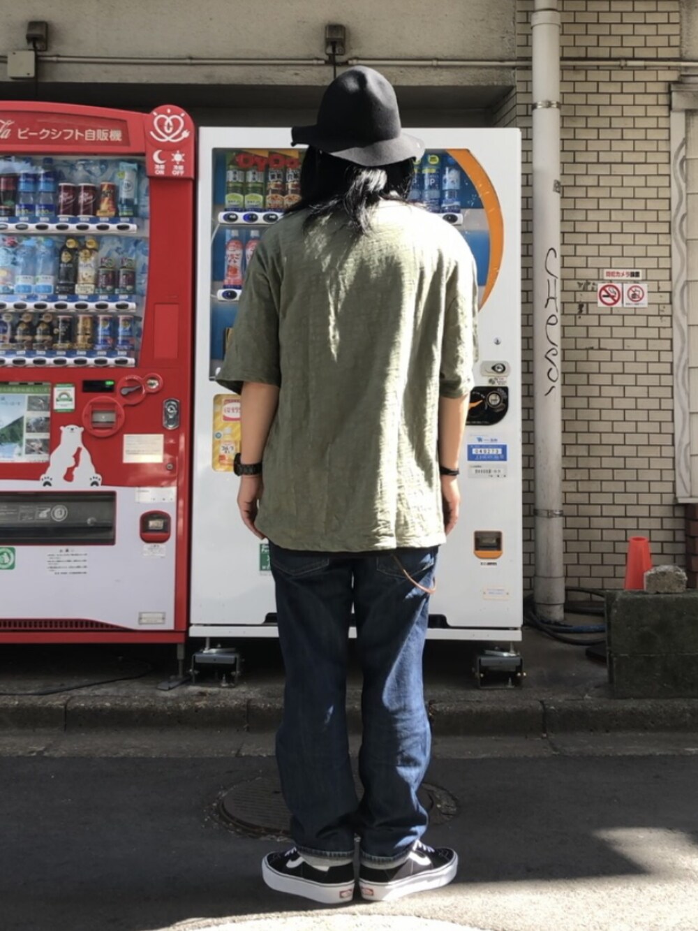 グリーン系のTシャツ/カットソー、ブラック系のスニーカー、ブルー系のデニムパンツを着用したメンズの秋コーディネートの4枚目の写真