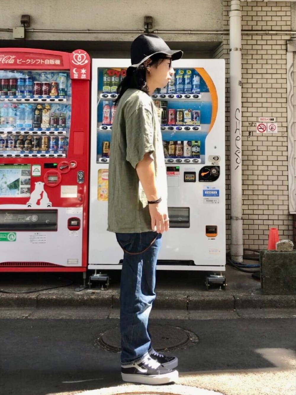 グリーン系のTシャツ/カットソー、ブラック系のスニーカー、ブルー系のデニムパンツを着用したメンズの秋コーディネートの3枚目の写真