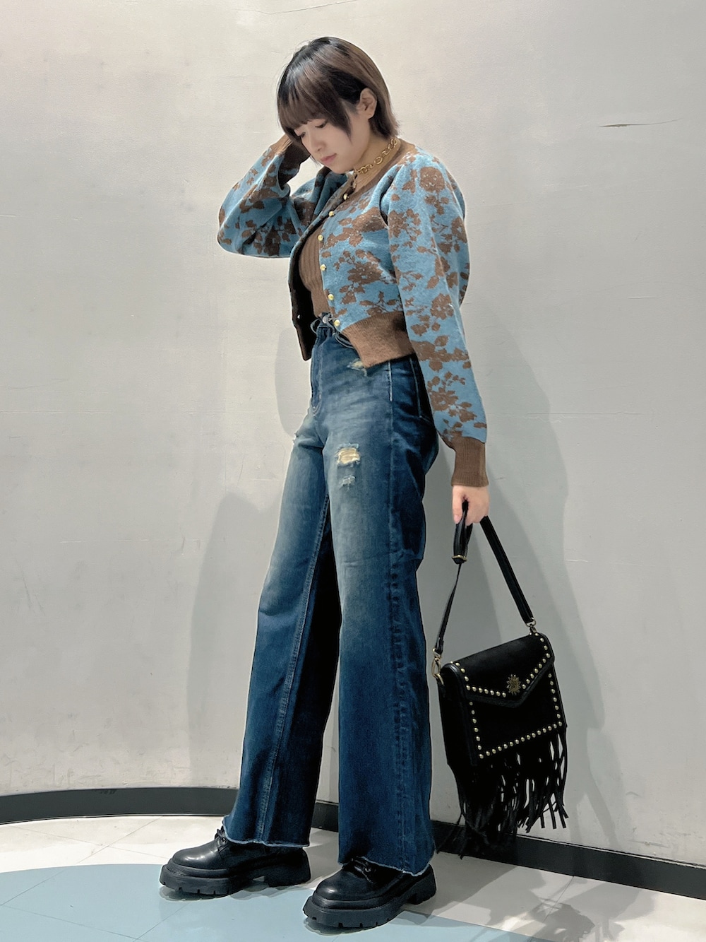 ブルー系のニット/セーター、ブルー系のデニムパンツ、ブラック系のショルダーバッグを着用したレディースの秋コーディネートの2枚目の写真