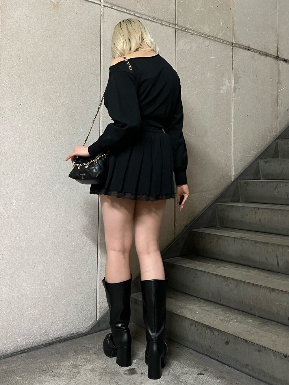 ブラック系のスウェット、ブラック系のショルダーバッグ、ブラック系のスカートを着用したレディースの春コーディネートの3枚目の写真