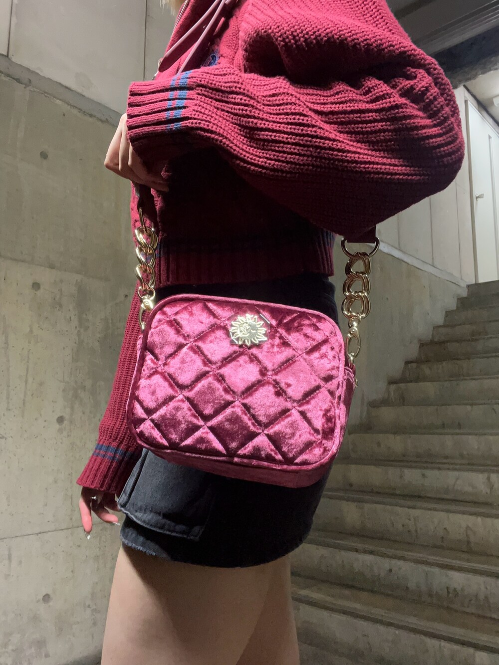 レッド系のニット/セーター、ピンク系のショルダーバッグ、ブラック系のデニムスカートを着用したレディースの秋コーディネートの6枚目の写真