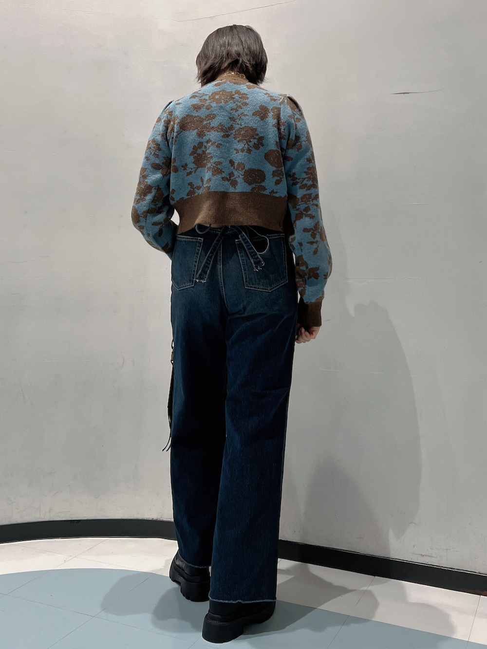 ブルー系のニット/セーター、ブルー系のデニムパンツ、ブラック系のショルダーバッグを着用したレディースの秋コーディネートの3枚目の写真