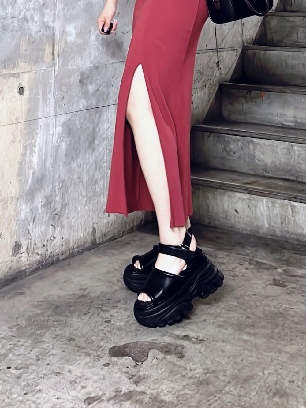 ブラック系のショルダーバッグ、ブラック系のサンダル、レッド系のワンピースを着用したレディースの夏コーディネートの5枚目の写真