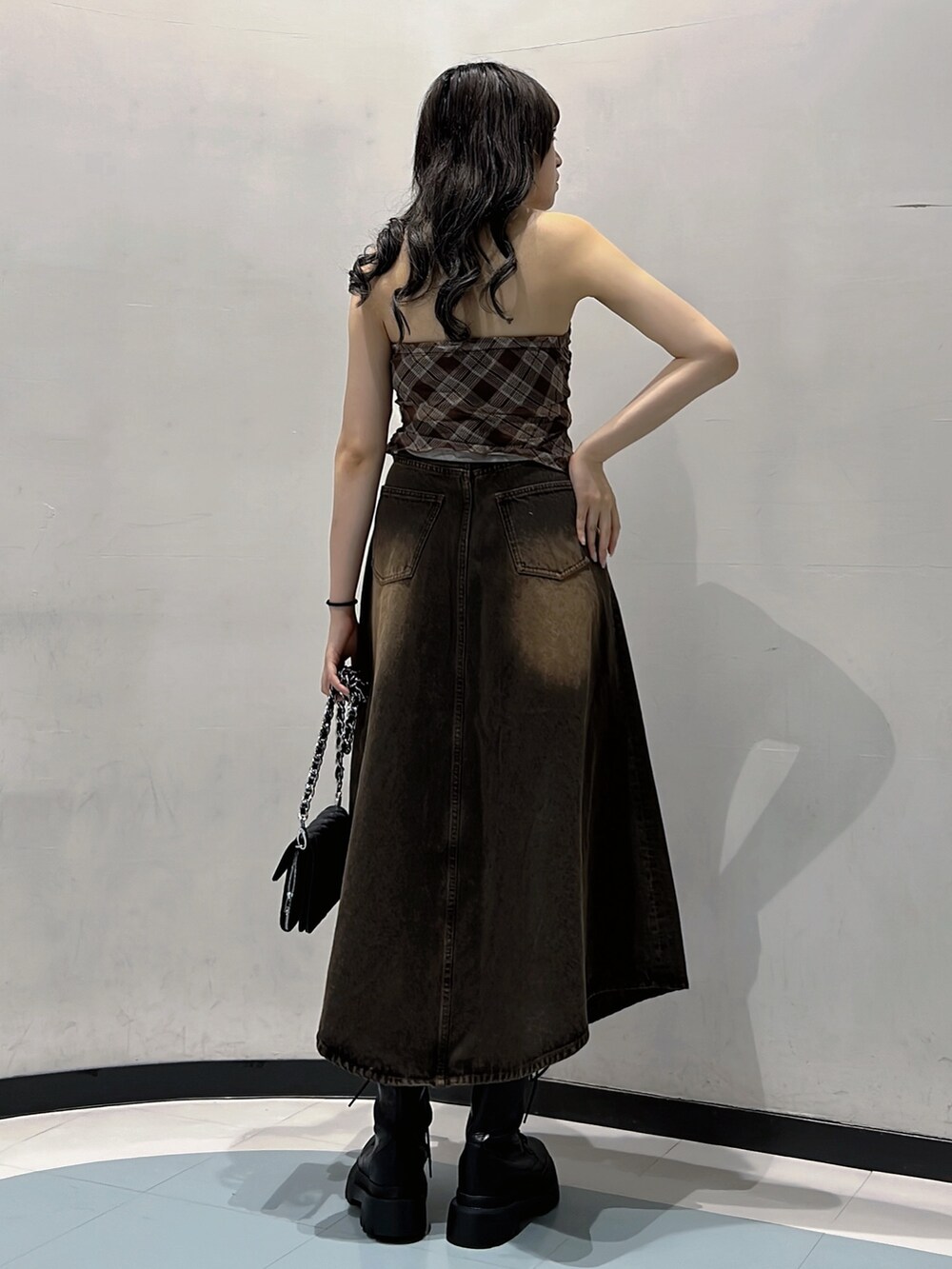 ブラウン系のキャミソール、ブラウン系のデニムスカート、ブラック系のハンドバッグを着用したレディースの秋コーディネートの3枚目の写真