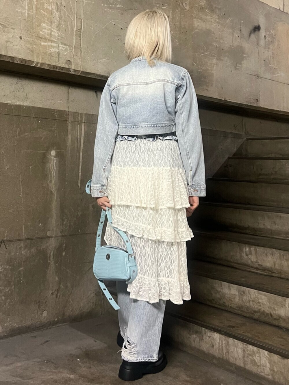 ブラック系のブーツ、ホワイト系のスカート、ブルー系のデニムジャケットを着用したレディースの冬コーディネートの3枚目の写真