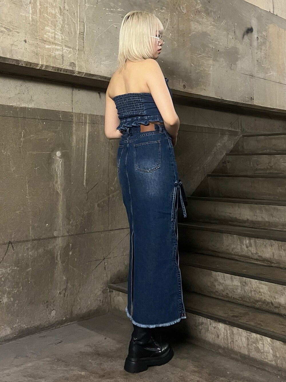 ブルー系のチューブトップ、ブルー系のハンドバッグ、ブルー系のデニムスカートを着用したレディースの春コーディネートの3枚目の写真