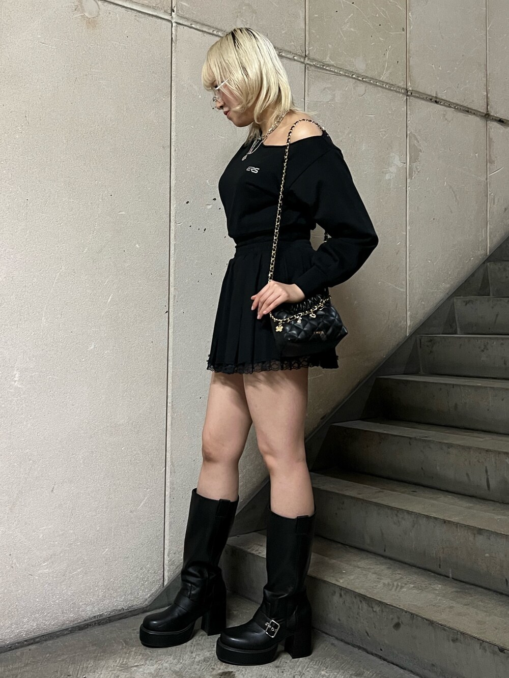 ブラック系のスウェット、ブラック系のショルダーバッグ、ブラック系のスカートを着用したレディースの春コーディネートの2枚目の写真